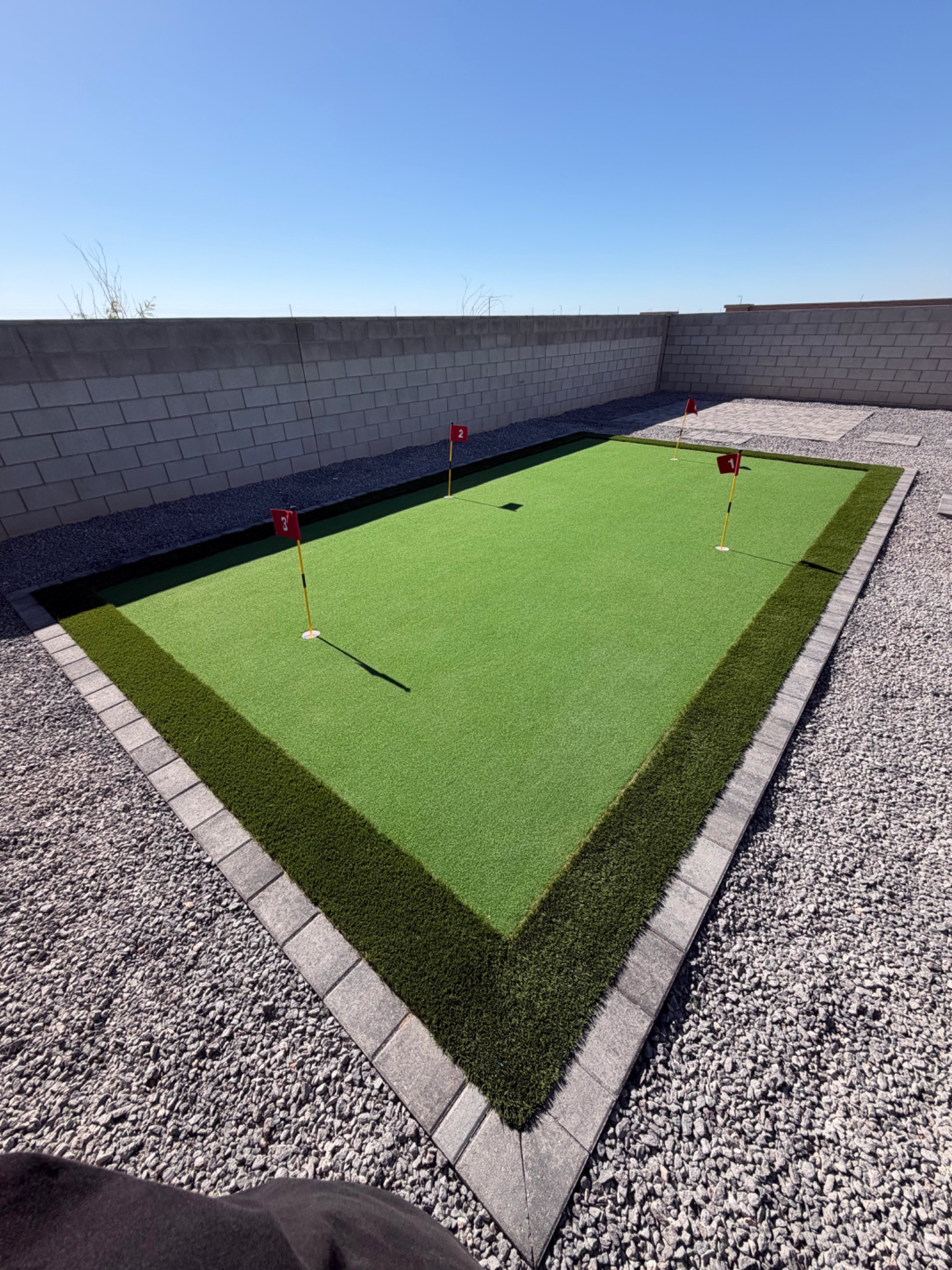 Artificial turf putting green with rock and paver border